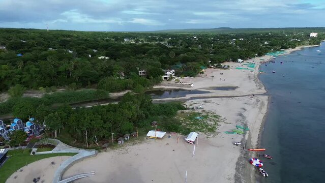 Long span of broad gently sloping strip of white fine sand beach lures resort developers to put up structures &ndash; Laiya, Batangas, Philippines. Aerial drone side panning tracking shot