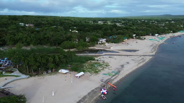 Long span of broad gently sloping strip of white fine sand beach lures resort developers to put up structures &ndash; Laiya, Batangas, Philippines. Aerial drone side panning tracking shot