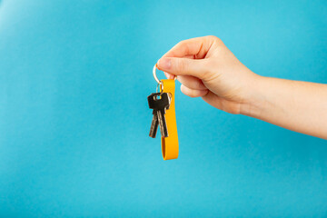 Keychain with a key ring in hand on a blue background. Concepts for real estate and moving home or...