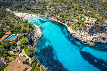 Aerial view with Cala Llombards secluded shores, where crystal-clear waters and golden sands create a peaceful haven on Mallorca coast.