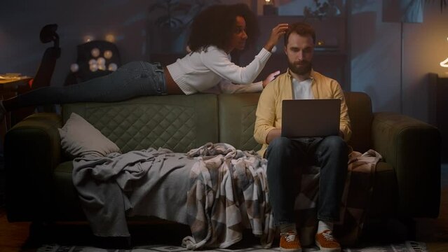 Happy relaxed pair holding gadgets at sofa resting at evening