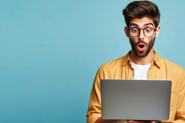 A man with glasses and a surprised look on his face is looking at a laptop on solid blue background. ai generative - obrazy, fototapety, plakaty