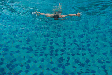 Top view of young man swimming front crawl in blue water