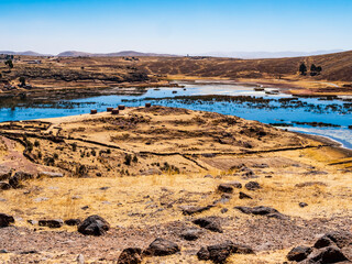 Panoramic view of Sillustani archeological site with arid lands and lagoon populated by flamingos, Puno region, Peru - 699733677