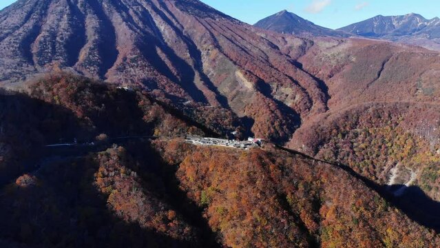 Autumn mountains, car parking and small ropeway to observation deck against Mount Nantai on background. Aerial shot of Nikko national park, Hosoomachi and Chugushi area