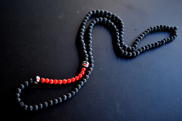 black and red beaded necklace on a black surface