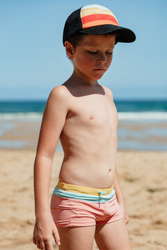 Thoughtful young boy on the beach with baseball cap