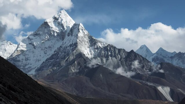 Covered with snow and glaciers summit Ama Dablam rises above barren landscape of himalayan mountains. Hiking to Nepal to see highest mountains in world. A sharp beautiful mountain peak