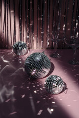 Three shiny disco balls indoors, color toned with two champagne glasses. New year concept. Space for text