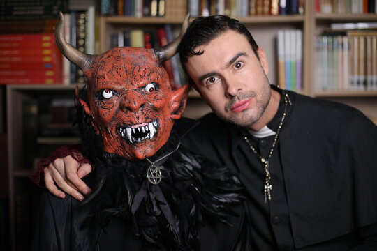 Man and friend dressed as demon and priest for Halloween taking a pic