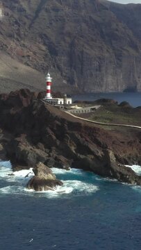 Aerial view of Punta de Teno lighthouse on Tenerife island, Spain. Beautiful landscape of rocky Tenerife coast with historic lighthouse, Canary Islands, Spain, vertical footage