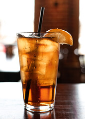Close up of a full glass of refreshing iced tea with a lemon wedge on a restaurant table