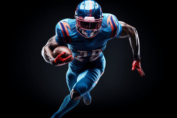 Portrait of American football player running with the ball. Muscular African American athlete in a blue and red uniform with an ovoid ball in a dynamic pose. Isolated on black background.