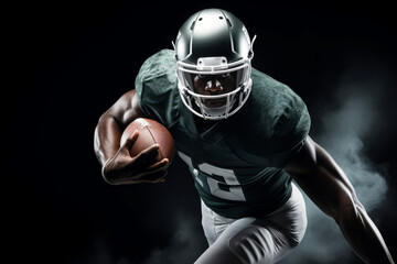 Portrait of American football player running with the ball. Muscular African American athlete in a green and white uniform with an ovoid ball in a dynamic pose. Isolated on black background.