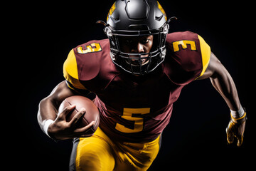 Portrait of American football player running with the ball. Muscular African American athlete in a burgundy and yellow uniform with an ovoid ball in a dynamic pose. Isolated on black background.