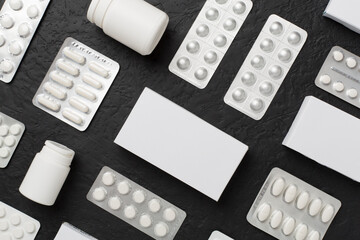 Different pills in blister packaging and boxes and on concrete background, top view