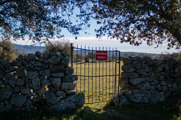 Translation: Private property. Private property sign Iron bar gate on a dry stone fence that gives...
