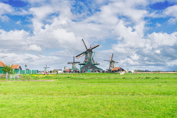 Fototapeta premium traditional Dutch scenery with windmill of Zaanse Schans with dramatic spring cloud sky, Netherlands