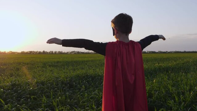A happy child playing a superhero. The child stands with arms outstretched to the sides, representing strength. Camera moves slowly around the circle