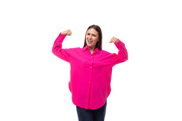 Obraz na płótnie Canvas energetic fashionable young brunette lady dressed in a bright pink shirt and jeans on a white background