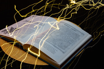 Otwarta książka na stole z żółtymi promieniami abstrakcja - obrazy, fototapety, plakaty
