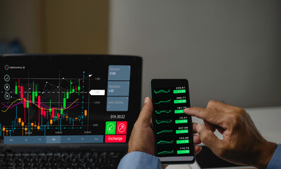  Trader using smartphone application and labtop for the  stock market to analyze trading charts and...