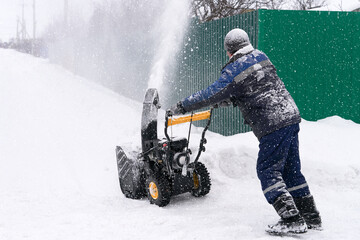 A man uses a compact snow blower to clear snow from a neighborhood after a snowstorm in the...