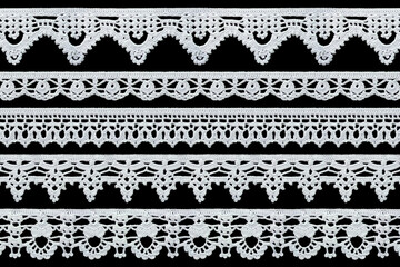 Set of white tape lace on a black background. The lace is crocheted by hand. Vintage style....