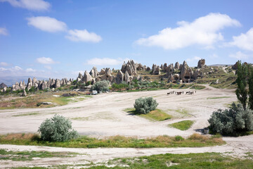 The unique fairy chimneys and rock formations of Cappadocia stand under a clear sky, with a...
