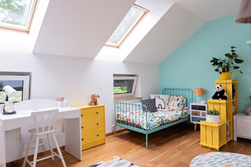 Room child in the attic with window, carpet in modern design on the wooden floor, white wall and yellow furniture. Cozy interior for teenager with desk, bed and sofa.	