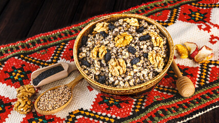 Ukrainian Christmas dish kutia, wheat porridge with nuts, poppy seeds, raisins in a vintage plate on the background of an embroidered towel. Ukrainian Christmas Eve