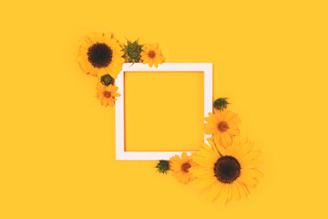 Square frame made of sunflowers and arnica flowers on a yellow background. Floral layout.