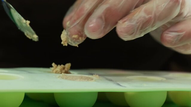 Culinarian puts pate into silicone mold to give paste spherical shape. Pate spheres serves as perfect decoration for fancy molecular dish