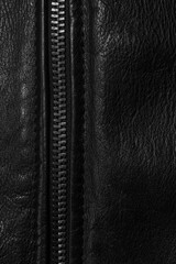 Black leather background with metal zipper close-up. Abstract dark leather texture