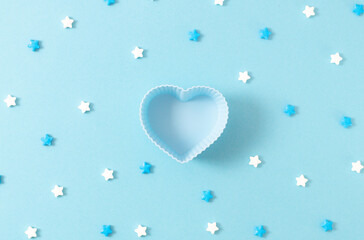 Muffin shape heart and candy sprinkles on a blue background.