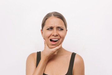 Young woman suffering from jaw pain holding her chin isolated on light background. Inflammation of...