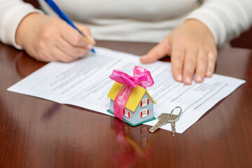 The client completes the paperwork, sealing the deal with a signature. A toy house decorated with a...