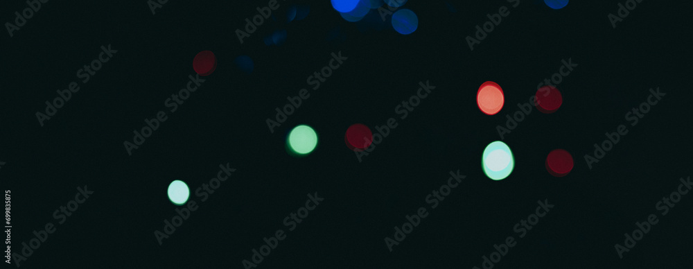 Poster dark backdrop with a multicolored bokeh effect from scattered, out-of-focus light spots.