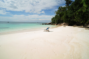 Blue empty beach chair on the sandy beach near the water in tropical Thailand, Asia. Travel...