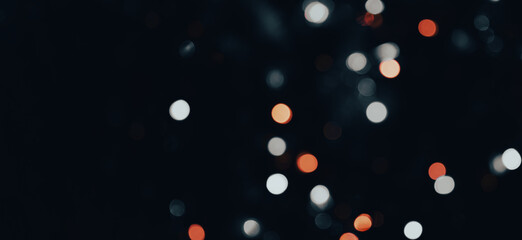 dark backdrop with a multicolored bokeh effect from scattered, out-of-focus light spots