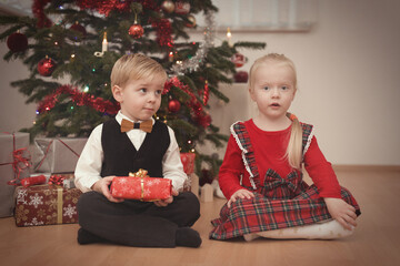 Children at time of christmas day unpacking gifts near tree