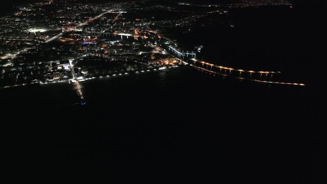 An enchanting drone film showcases Kołobrzeg's lighthouse and winter-night pier, blending coastal beauty with a serene ambiance and captivating nocturnal lights. Kolobrzeg, Poland.