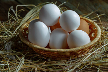 Chicken eggs, in a nest of feathered blades of grass, on an old background.