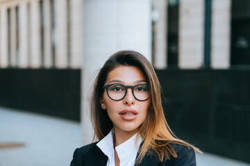 businesswoman in eyeglasses and business suit, portrait with architectural elements.