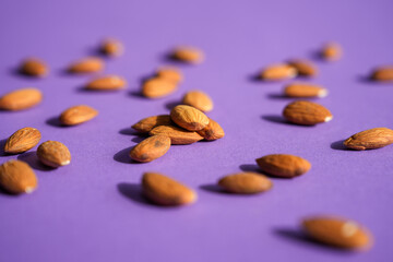 Almonds lying on a purple background