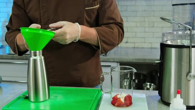Man prepares utensils to filter sauce from sediment with metal sieve. Restaurant culinarian prepares fruit condiment for delicacy dish