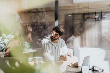 A diverse group of professionals in a sunlit office collaborating on business ideas and strategies, creating a positive atmosphere for successful teamwork.