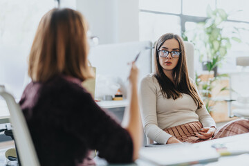 Female employees discussing financial analysis and marketing strategy in the workplace.