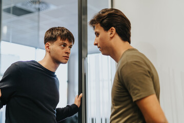 Two good looking male friends, colleagues, having serious conversation while taking a break from work.