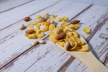 Beakfast cereals in wooden spoon. Healthy muesli with oat flakes, nuts and raisins isolated on white background.